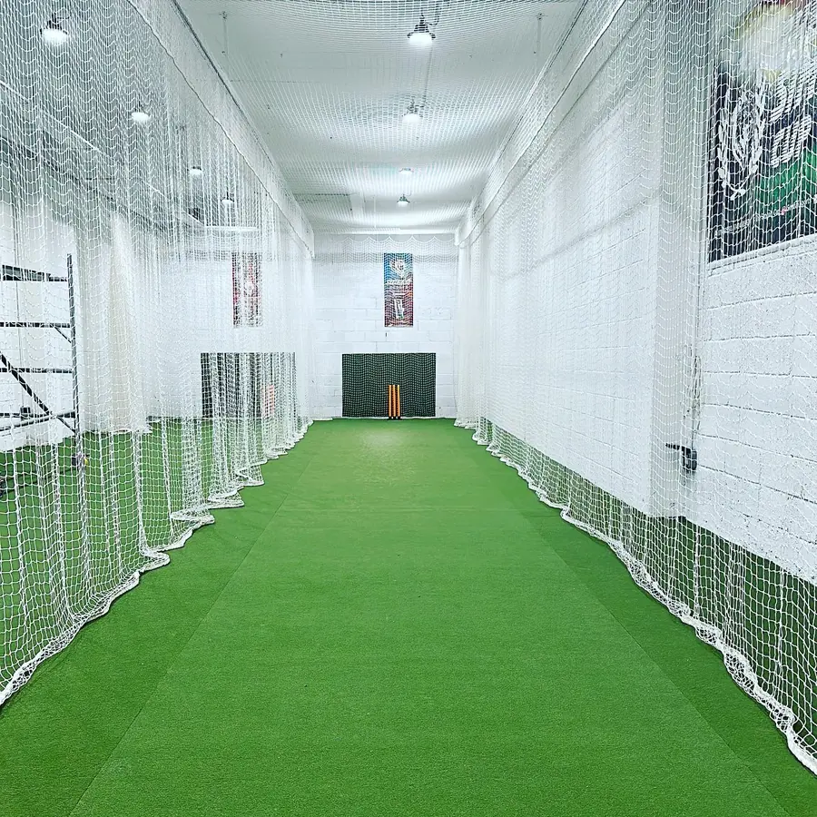 Simbah Sports indoor cricket lane — artificial turf, netting between lanes and stumps at the far end